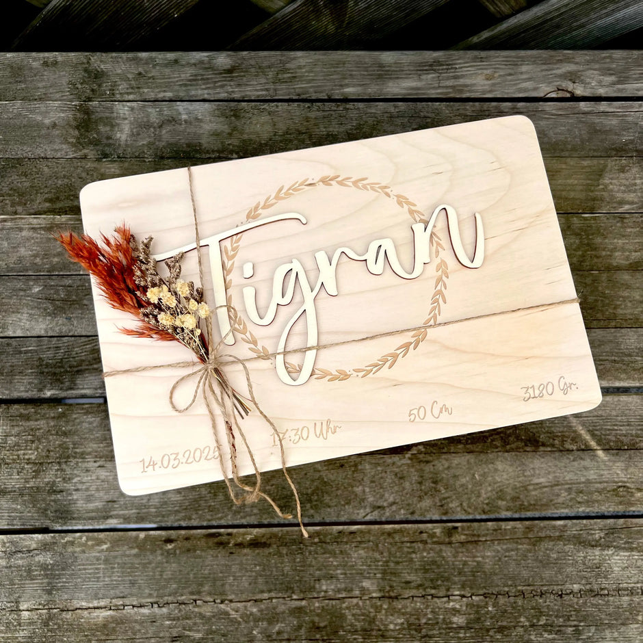 Personalisierte Holztafel mit dem Namen im 3D-Schriftzug, umrahmt von einem Blätterkranz