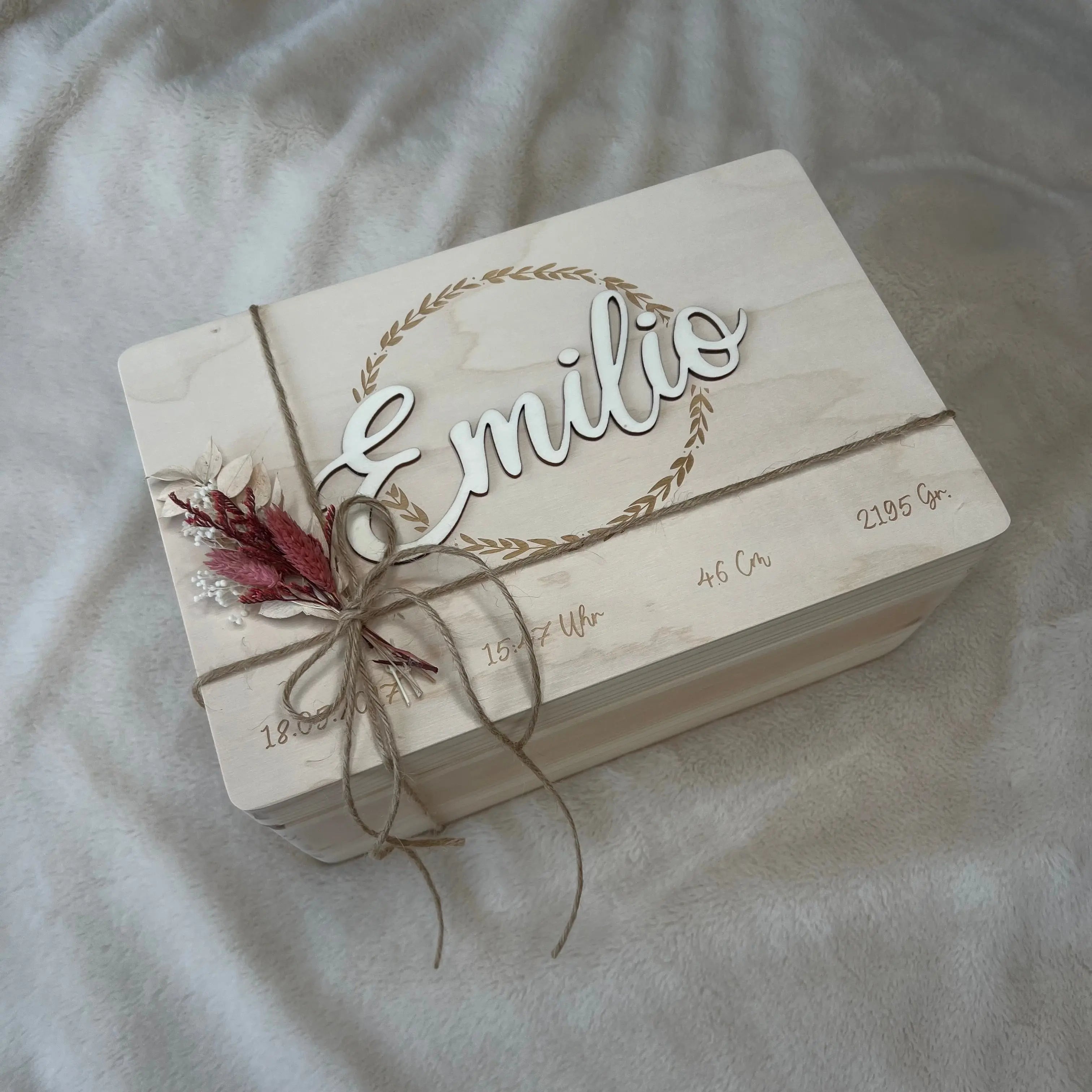 Personalisierte Holztafel mit dem Namen Emilio im 3D-Schriftzug, umrahmt von einem Blätterkranz