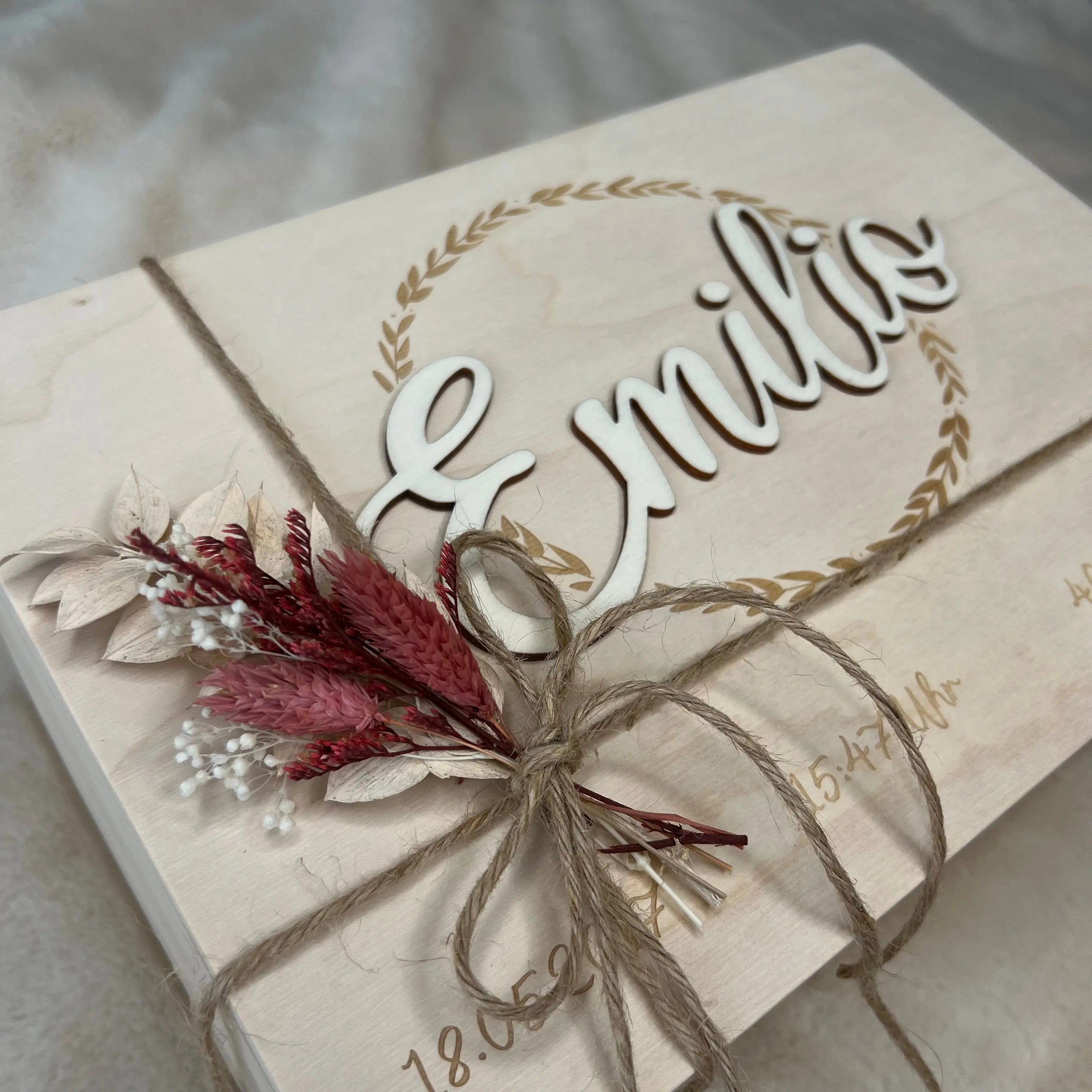 Personalisierte Holztafel mit dem Namen Emilio im 3D-Schriftzug, umrahmt von einem Blätterkranz